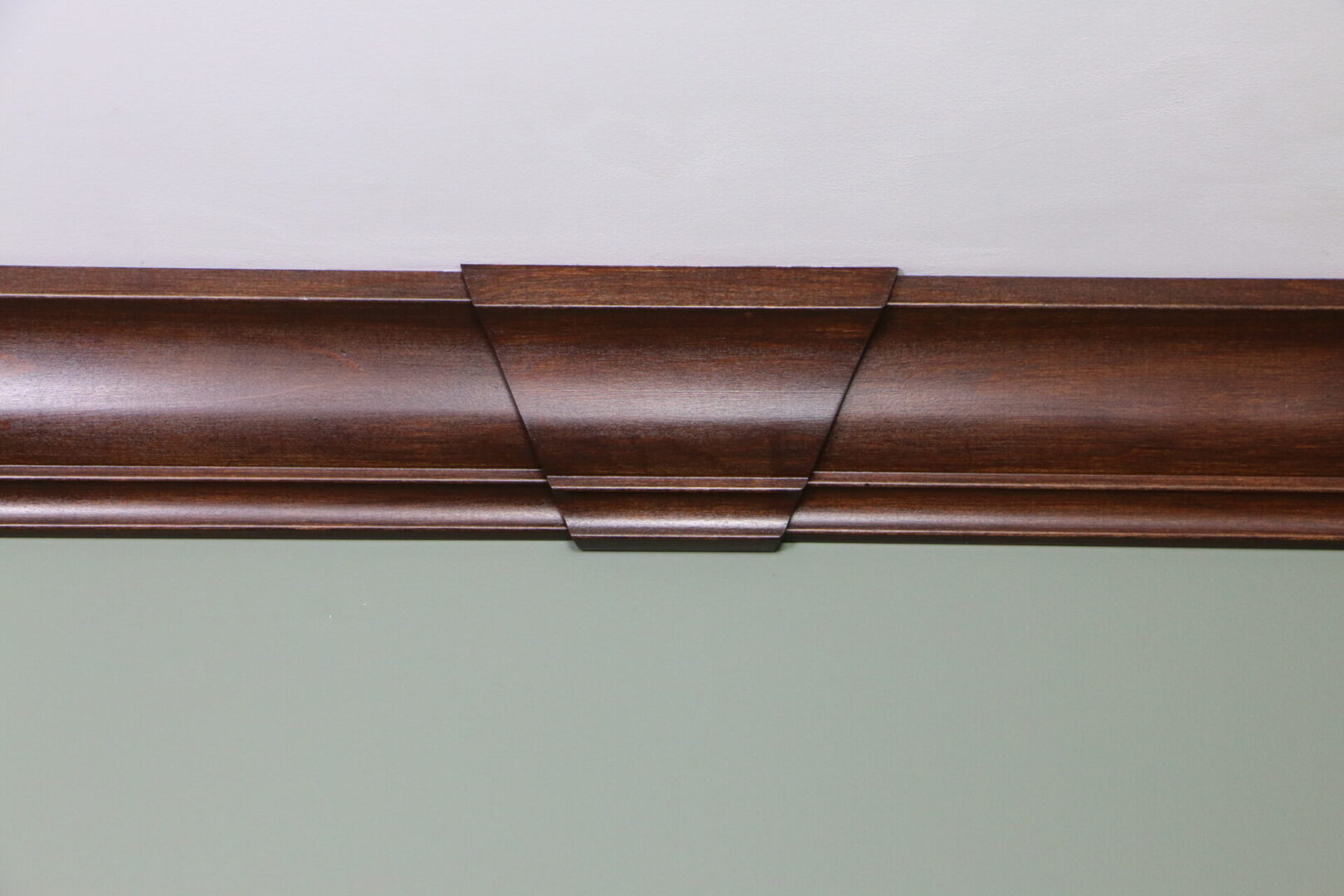 A wooden crown molding on the wall above a window.